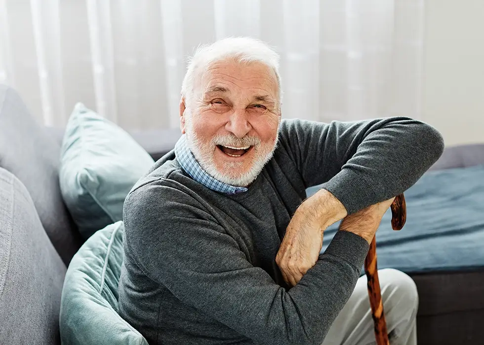 Porträt eines behinderten älteren Mannes mit Gehstock zu Hause.